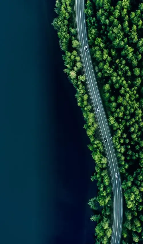 Aerial view of four cars driving on a highway near a body of water